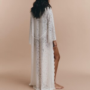 May include: A white lace robe with long sleeves and a flowing silhouette.