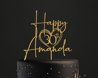 Pode incluir: Um bolo preto de dois andares com glitter dourado e decorações florais pretas. Um topo dourado com o texto "Happy 30th Amanda" está no topo do bolo.