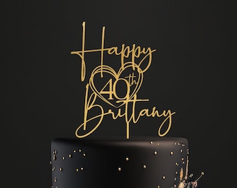 May include: A black two-tier cake with gold accents and a gold topper that says "Happy 40th Brittany".