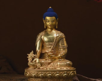 May include: A golden Buddha statue with a blue crown sits in a meditative pose on a gold base. The statue is detailed with intricate carvings and a serene expression.