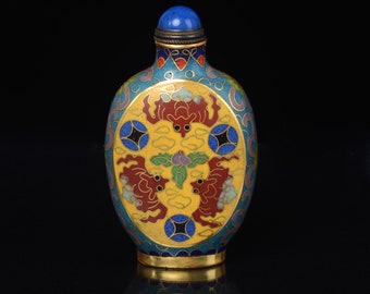 May include: A small, oval-shaped, blue and yellow enamel bottle with a gold lid and a blue stone top. The bottle is decorated with a red and gold floral design.