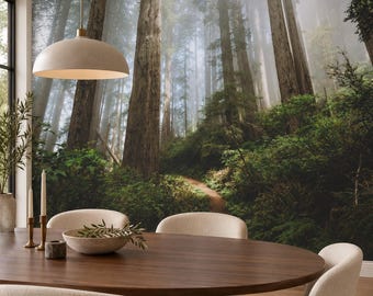 May include: A dining room featuring a large oval wooden table surrounded by four cream-colored upholstered chairs. A bowl with greenery sits on the table, beneath a pendant light. A wall mural depicts a misty forest with tall trees.