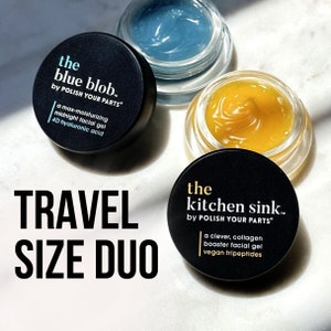 May include: Two small jars of facial skincare products, labeled "the blue blob" and "the kitchen sink", both by "POLISH YOUR PARTS". The jars are on a white marble surface with the text "TRAVEL SIZE DUO" in black.