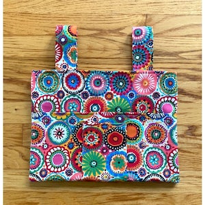 Könnte beinhalten: Ein farbenfroher Stofforganizer mit zwei Trägern. Der Stoff hat ein Muster aus Kreisen in verschiedenen Farben und Designs. Der Organizer hat eine Tasche auf der Vorderseite.