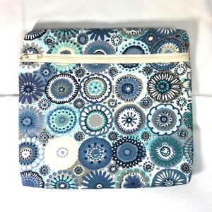 May include: A zippered pouch with a white background and a blue and gray floral pattern. The pouch has a zipper closure.