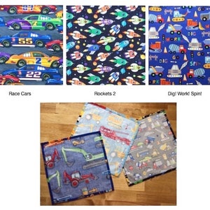 May include: Three square fabric cloths featuring colorful patterns: one with race cars, one with rockets in space, and one with construction vehicles, traffic cones, and the text Dig! Work! Spin! printed on a blue background.