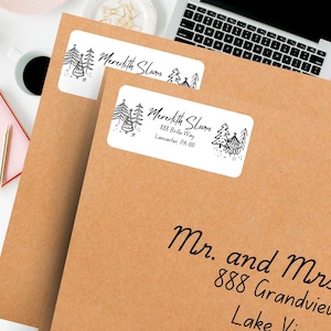 May include: Two white return address labels with a black and white illustration of Christmas trees. The top label reads "Meredith Sloan". The bottom label reads "Meredith Sloan, 888 Brilla Way, Lancaster, PA".