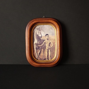 May include: A framed print featuring a boy and a horse. The artwork is in a wooden oval frame with a gold inner border. The boy is standing next to the horse, with his hand on the horse's neck. The background is a muted landscape.