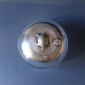 May include: A silver lidded glass jar with a turtle design on the top.