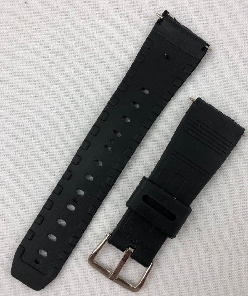 Puede incluir: Correa de reloj de goma negra con hebilla plateada. La correa tiene una superficie texturizada y est&aacute; dise&ntilde;ada para un reloj de pulsera.