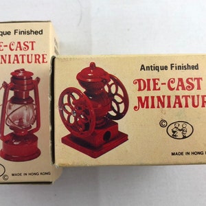May include: Two antique finished die-cast miniature pencil sharpeners in boxes. One is a red lantern and the other is a red coffee grinder. Both boxes have the text "Antique Finished Die-Cast Miniature" and "Made in Hong Kong".