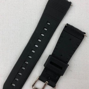 Puede incluir: Correa de reloj de goma negra con hebilla plateada. La correa tiene una superficie texturizada y est&aacute; dise&ntilde;ada para un reloj de pulsera.