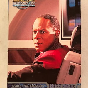 May include: A Star Trek: Deep Space Nine trading card featuring Sisko, "The Emissary." The card has the text "Greatest Moments" and "Memories From The Future." The image shows Sisko in a red and black uniform.