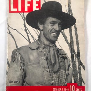 May include: Vintage LIFE magazine cover featuring Gary Cooper. The cover has a red banner with the text "LIFE" in white, and the date "October 7, 1940". Cooper is wearing a black hat, a fringed vest, and a patterned shirt, smiling at the viewer.