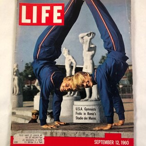 May include: A vintage LIFE magazine cover featuring two USA gymnasts in blue tracksuits performing a handstand. The cover has the word "LIFE" in large red letters at the top. The date "SEPTEMBER 12, 1960" is printed at the bottom.
