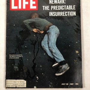 May include: A LIFE magazine cover from July 28, 1967, featuring a black and white photo of a young man lying on the ground in a street. The headline reads "NEWARK: THE PREDICTABLE INSURRECTION".