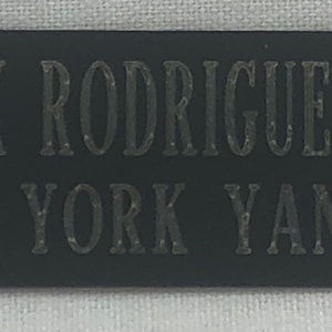 May include: Black rectangular nameplate with silver lettering. The nameplate reads "ALEX RODRIGUEZ #13 NEW YORK YANKEES".