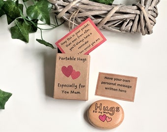 May include: A small wooden box with a red and white card that reads "Keep this in your pocket, then even from afar, you'll always have a reminder + how special you are". The box is labeled "Portable Hugs" and "Especially for You Mum". A small wooden heart-shaped stone with the words "Hugs For my Mum" is next to the box.