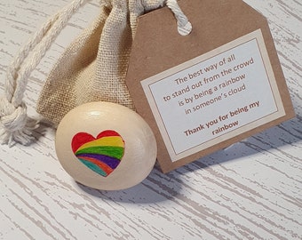 May include: A small wooden heart with a rainbow painted inside. The heart is in a burlap bag with a brown tag that reads "The best way of all to stand out from the crowd is by being a rainbow in someone's cloud. Thank you for being my rainbow."