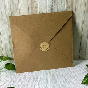 Puede incluir: Un sobre de papel marr&oacute;n con una pegatina redonda que dice "handmade with love" en letras negras.