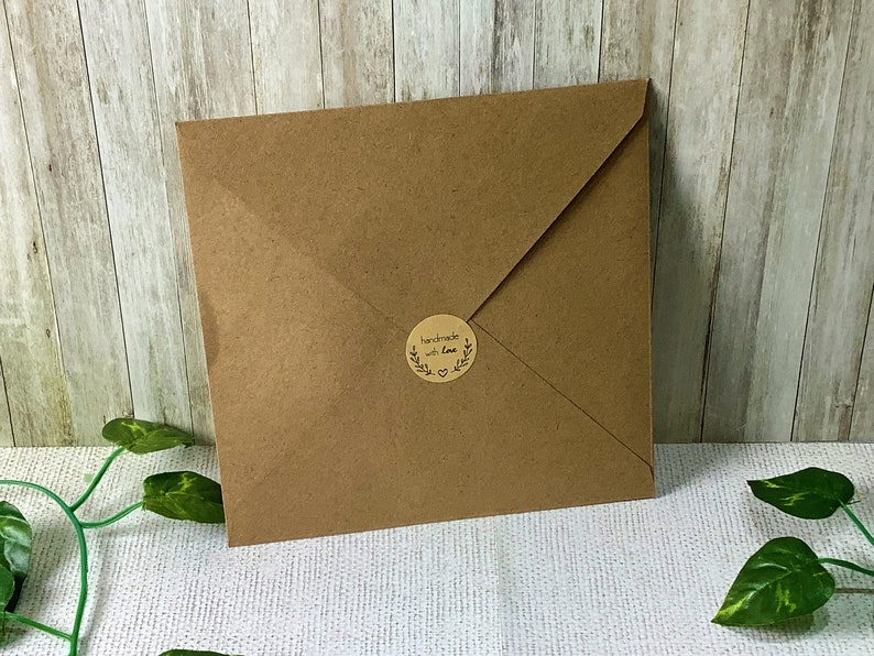 Puede incluir: Un sobre de papel marr&oacute;n con una pegatina redonda que dice "handmade with love" en letras negras.
