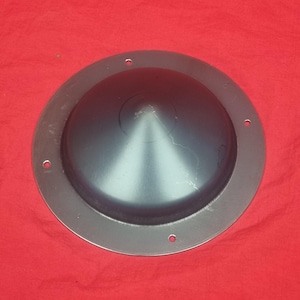 May include: A silver metal shield with a domed centre and a raised rim. The shield has six evenly spaced holes around the rim.