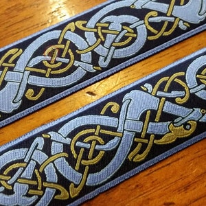 Könnte beinhalten: Blau-goldenes keltisches Knotenband mit einem sich wiederholenden Muster aus verschlungenen Knoten. Das Band ist mit einem dunkelblauen Hintergrund, hellblauen Knoten und goldenen Akzenten gewebt.