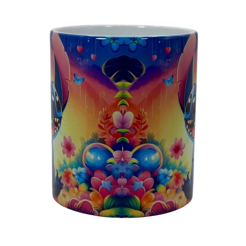 May include: A ceramic mug featuring a colorful design with a cartoon character, flowers, butterflies, and hearts. The mug has a white interior and a vibrant, wraparound print with shades of blue, pink, yellow, and orange.