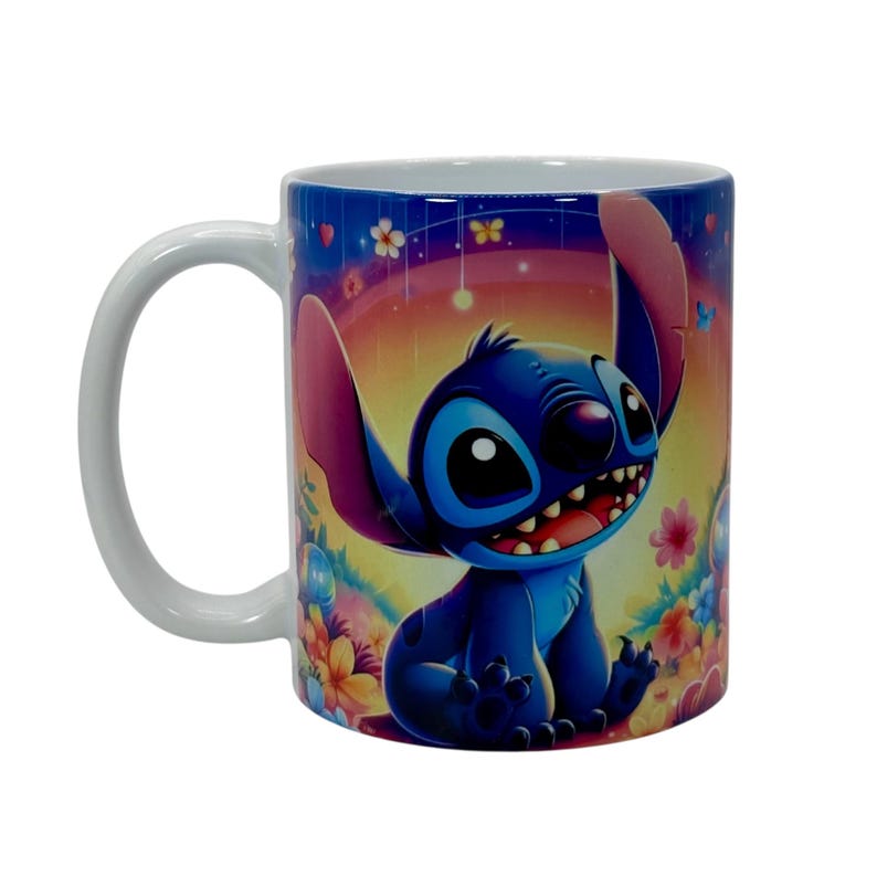 May include: A white ceramic mug featuring a colorful illustration of Stitch from Lilo & Stitch. The blue alien is smiling with a rainbow and floral background. The mug has a white handle.