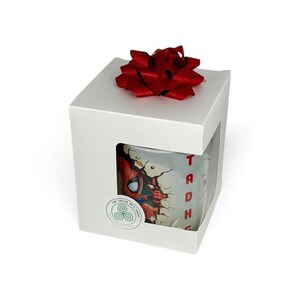 May include: A white gift box with a red bow on top. The box has a window showing a Spider-Man mug. The mug features a graphic of Spider-Man breaking through a wall, with the name "Tadhg" in red.