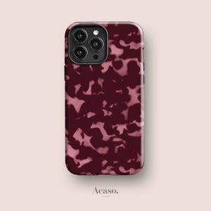 May include: A smartphone case featuring a dark burgundy and light pink mottled pattern. The case has a cutout for a triple-lens camera system on the back. The word Acaso. is printed in small black letters below the phone case on the light background.