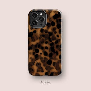 Op de afbeelding: Een rechthoekig smartphonehoesje met een bruin en zwart schildpadpatroon. Het hoesje heeft een uitsparing in de linkerbovenhoek voor een camerasysteem met drie lenzen. Het woord Acaso. staat in kleine zwarte letters onder het hoesje gedrukt.