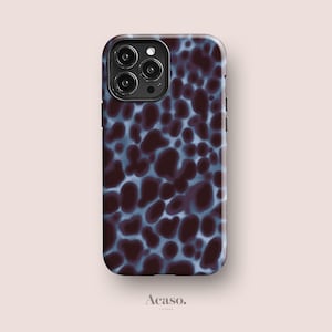 May include: A rectangular smartphone case featuring a dark brown and light blue mottled animal print pattern. The case has a cutout for a triple-lens camera system on the top left corner. The word Acaso. is printed in small black text below the case.