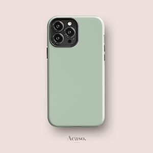 May include: A sage green smartphone case with a smooth matte finish and a black camera module housing three circular lenses and a flash. The case features a rectangular shape with rounded corners and the text Acaso. London at the bottom.