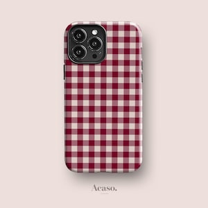 May include: A smartphone case featuring a dark red and cream-coloured gingham check pattern. The case has a black camera module cutout with three circular lenses and a flash. The word Acaso. is printed in small black text below the case.
