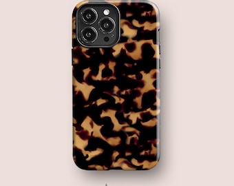 Peut inclure: Une coque de smartphone avec un motif écaille de tortue brun foncé et ambre. La coque est rectangulaire avec des coins arrondis et une découpe pour un système de triple objectif. Le mot Acaso. est imprimé en petit texte noir sous la coque.