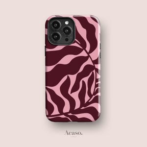 May include: A rectangular smartphone case featuring a repeating pattern of dark burgundy organic leaf shapes set against a light pink background. The case includes a black camera cutout module at the top left corner and the text Acaso. at the bottom.