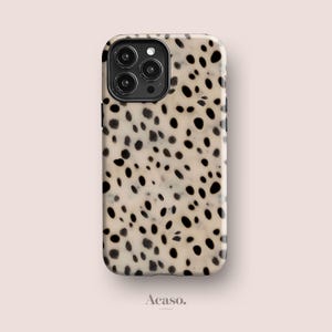Peut inclure: Une coque de smartphone rectangulaire présentant un fond crème avec un motif intégral de taches noires irrégulières. La coque comprend une découpe noire pour le module photo dans le coin supérieur gauche. Le texte Acaso. est imprimé sous la coque.