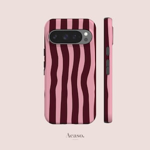Pode incluir: Uma capa de smartphone com um padrão de listras verticais onduladas em tons alternados de bordô escuro e rosa claro. A capa exibe um recorte para a câmera traseira e botões laterais na borda direita. O texto Acaso. está abaixo.