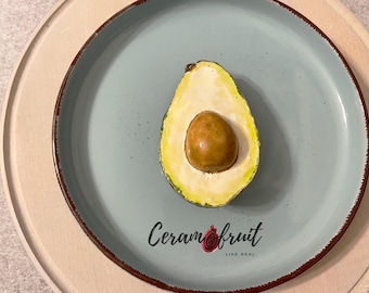 Half of an avocado. Ceramics. Decorative item. Natural size. Glaze. Festive table decoration. Interior decoration.