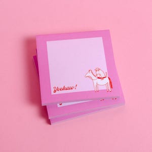 May include: Pink sticky notes with a white central area and a red illustration of a horse and cat. The text "Yeehaw!" is printed in red. The notes are stacked on a pink background.