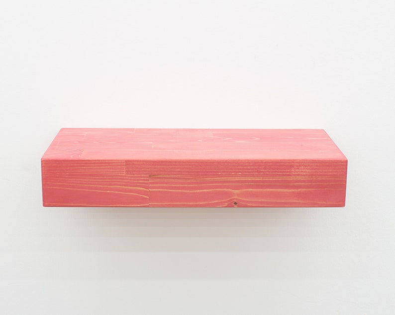 May include: A solid wood shelf painted a bright pink color. The shelf is made of natural wood with visible grain.