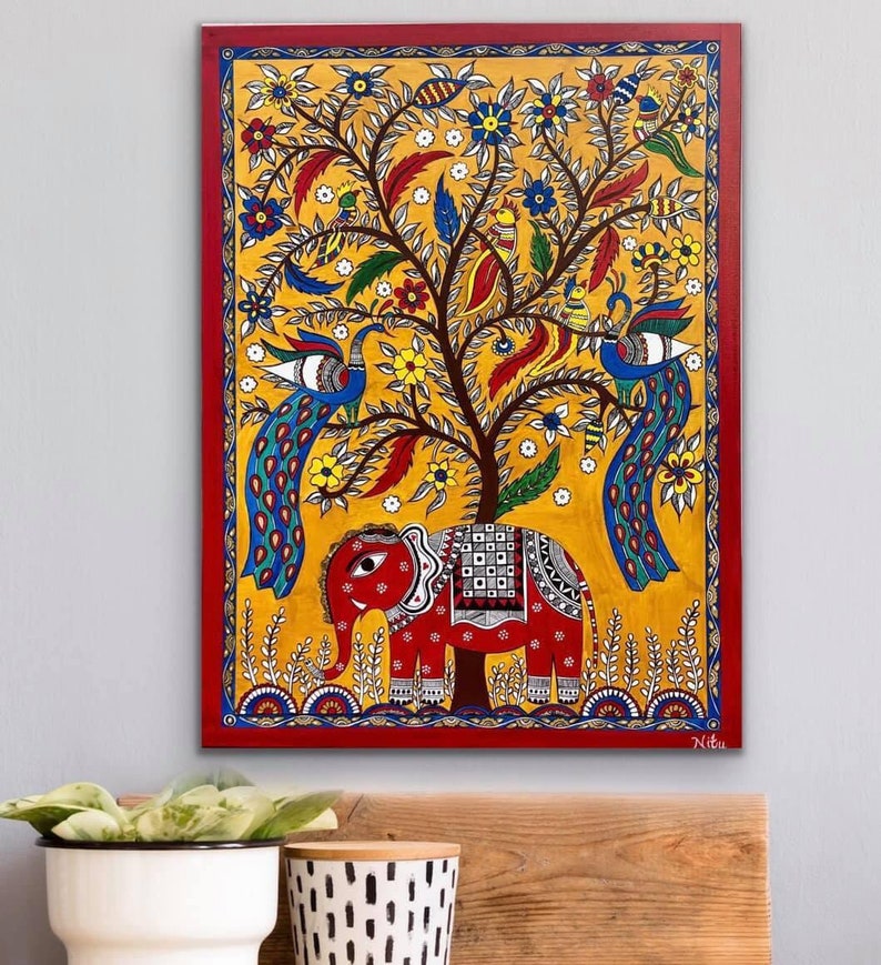 Puede incluir: Una pintura colorida de un &aacute;rbol con pavos reales y un elefante. El &aacute;rbol est&aacute; pintado en tonos de amarillo, verde y marr&oacute;n, con flores rojas, azules y amarillas. Los pavos reales son azules y verdes con acentos amarillos y rojos. El elefante es rojo con detalles en blanco y negro. La pintura est&aacute; enmarcada en un marco rojo.