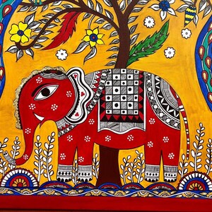 Puede incluir: Una pintura de arte popular colorida de un elefante rojo con detalles en blanco y negro de pie frente a un fondo amarillo con un &aacute;rbol verde y pavos reales azules. El elefante tiene un ojo blanco y una defensa blanca. La pintura est&aacute; enmarcada en un marco rojo y dorado.