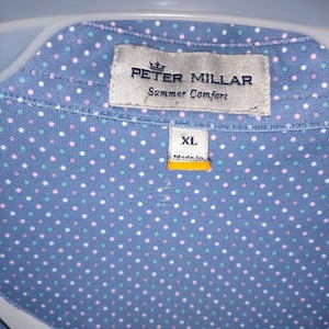 以下が含まれることがあります： 白、ピンク、緑のドット柄の青いボタンダウンシャツ。シャツには「Summer Comfort」という文字の入ったPeter Millarのラベルと、「XL」と書かれたサイズタグが付いています。