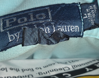 Peut inclure: Une étiquette de vêtement bleue Polo by Ralph Lauren avec du texte blanc.
