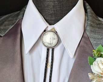 May include: A white and silver bolo tie with a white marble-like stone in the center. The bolo tie is worn on a white dress shirt with a gray suit jacket.