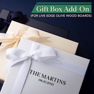 May include: Three gift boxes with satin ribbon bows. The boxes are in cream, black, and white. The white box has the text "THE MARTINS" and the date "08.10.2021". The image also includes the text "Gift Box Add-On (FOR LIVE EDGE OLIVE WOOD BOARDS)".