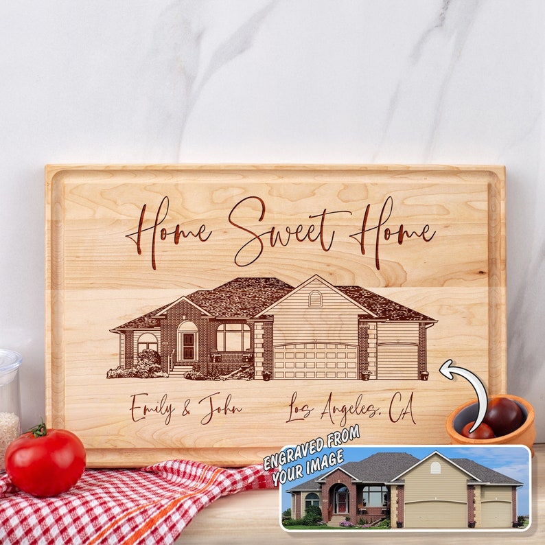 Puede incluir: Una tabla de cortar de madera personalizada con una imagen grabada con l&aacute;ser de una casa. El texto "Home Sweet Home" est&aacute; grabado sobre la casa. Los nombres "Emily & John" y la ubicaci&oacute;n "Los Angeles, CA" est&aacute;n grabados debajo de la casa. El texto "Engraved from your image" tambi&eacute;n est&aacute; grabado en la tabla.
