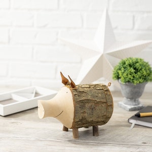 May include: A wooden pig figurine with a brown bark-like texture and a light brown snout. The pig has small brown ears and stands on four wooden legs.